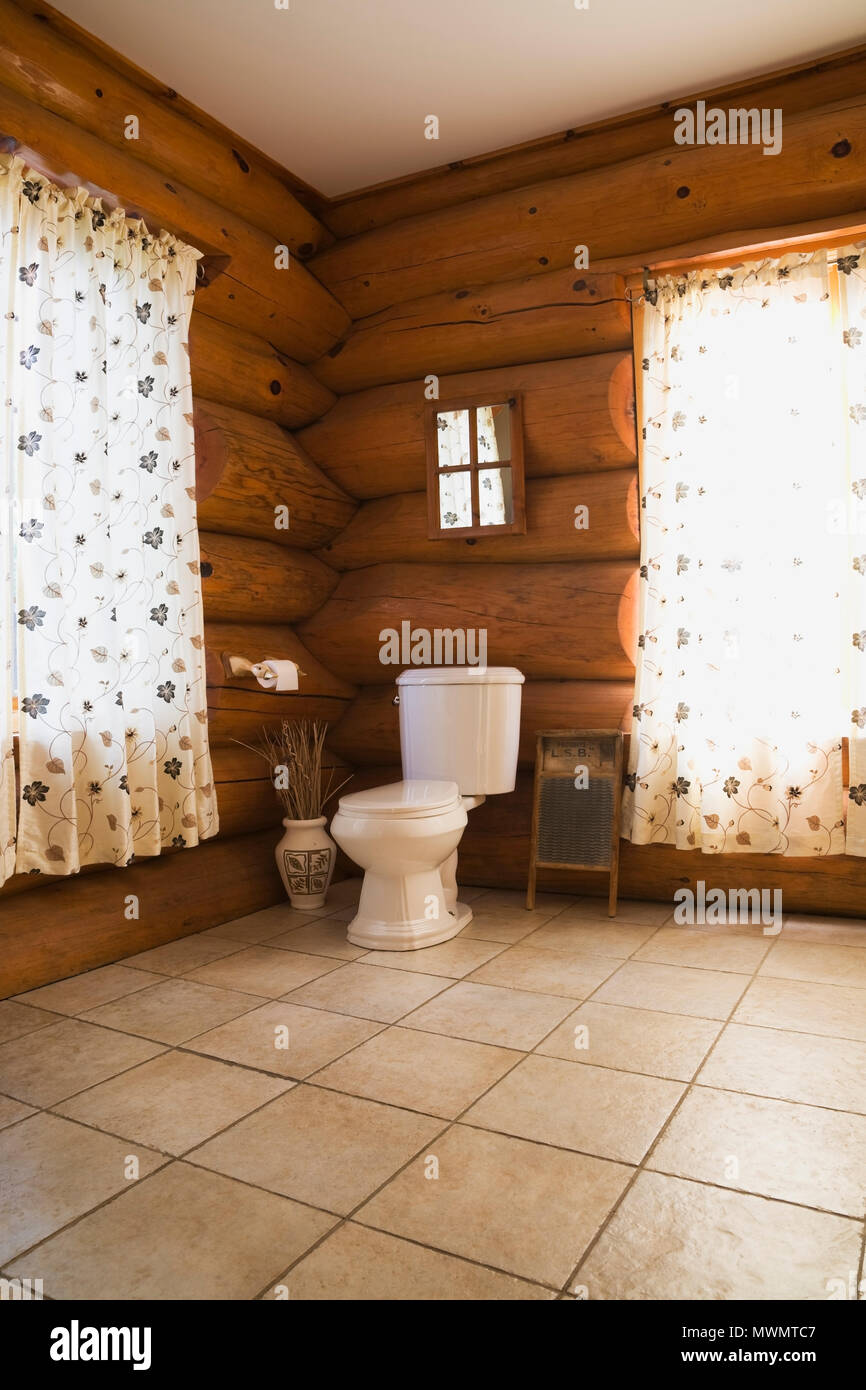 Toilet in corner of main bathroom inside a cottage style log home Stock