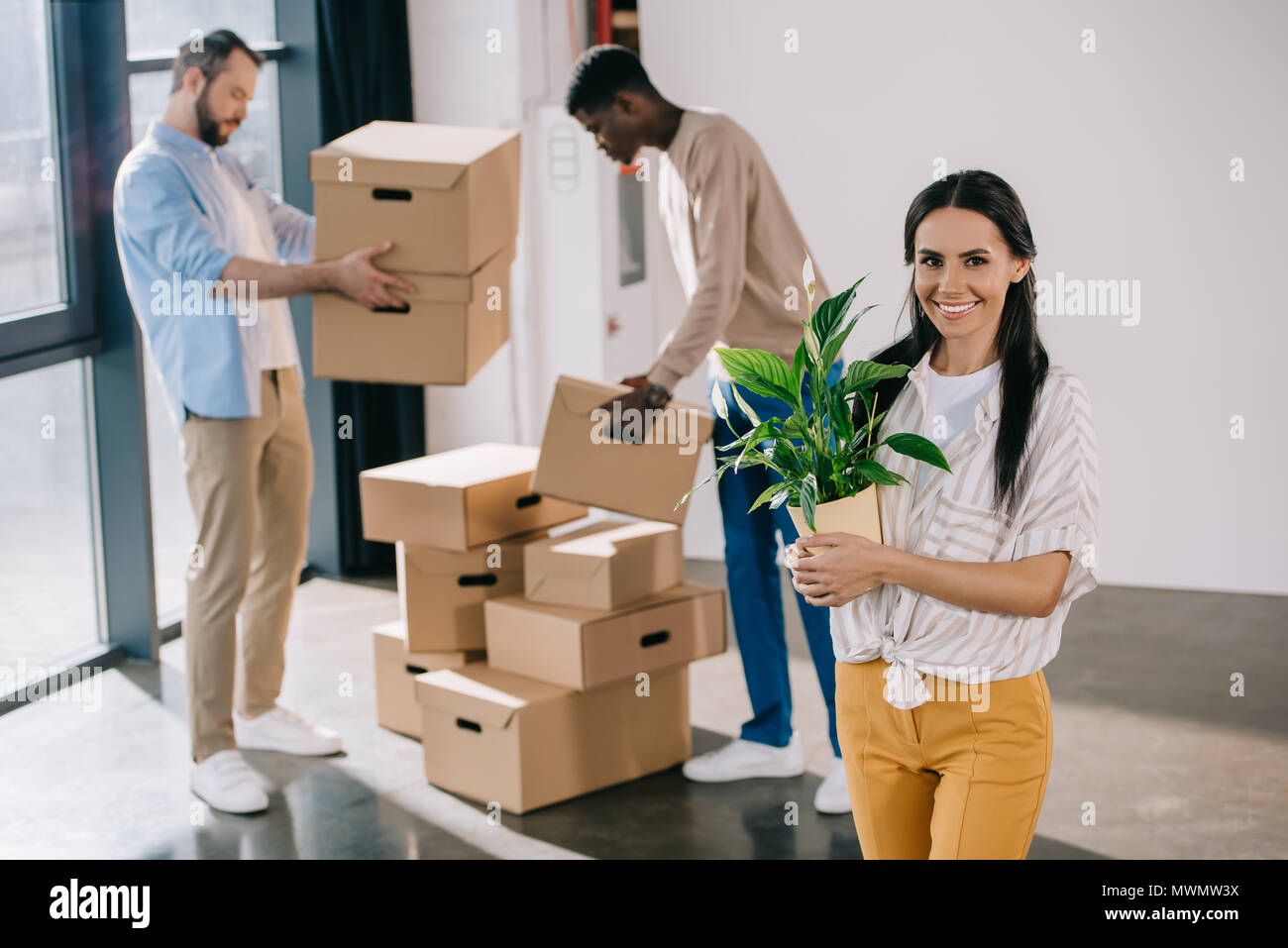 young woman holding potted plant and smiling at camera while male ...