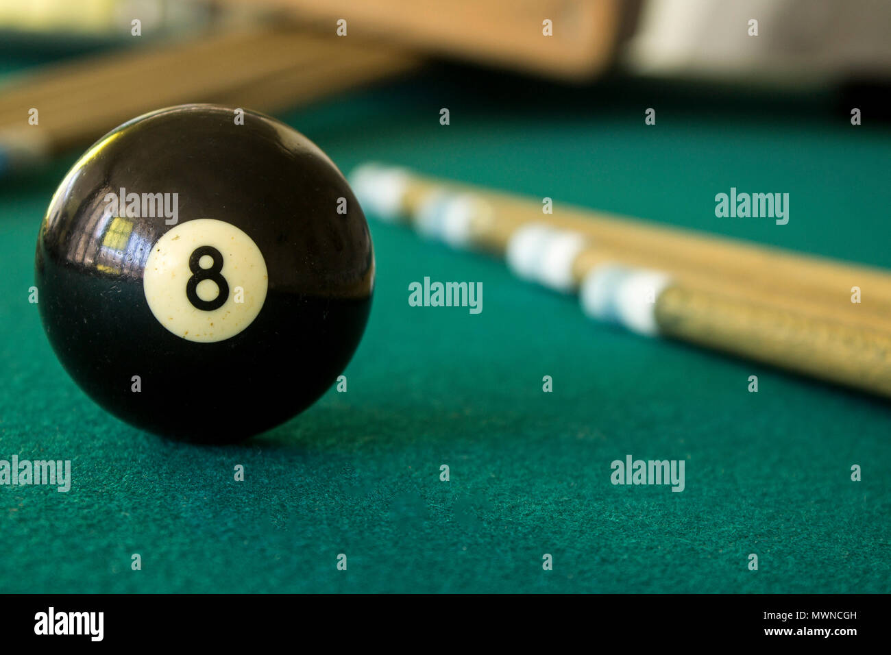 Eight black ball on a green table with cue sticks Stock Photo
