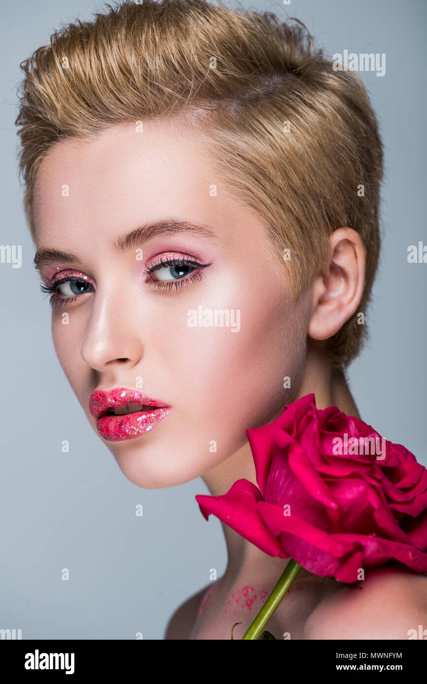 portrait of attractive woman with glitter on lips and red rose isolated on grey Stock Photo