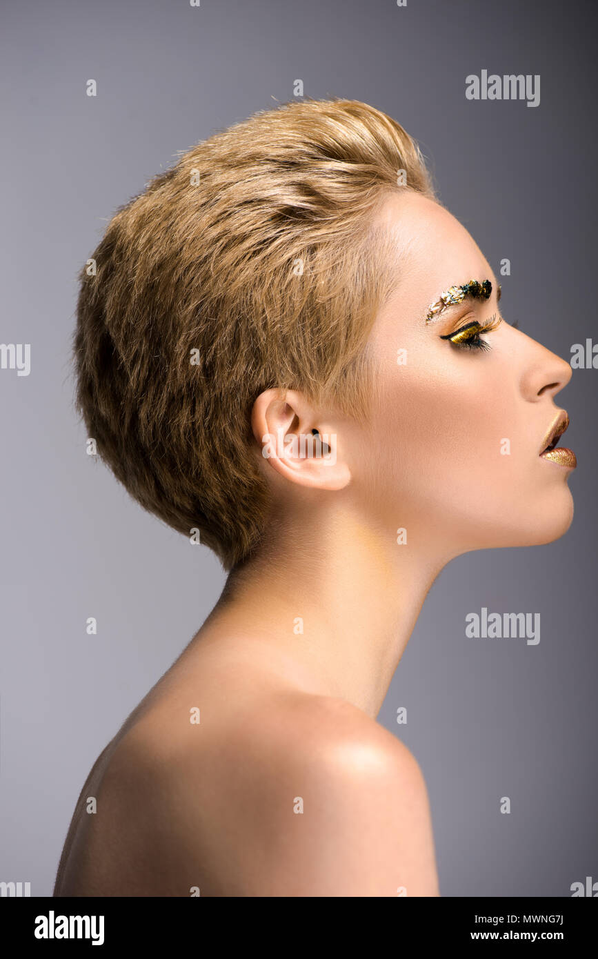 side view of attractive woman with golden glitter on face and short hair  isolated on grey Stock Photo - Alamy