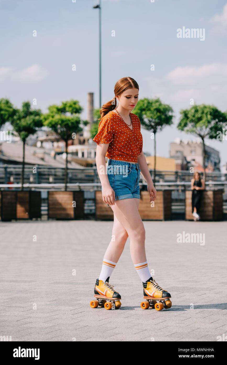full length view of attractive girl in denim shorts roller skating on