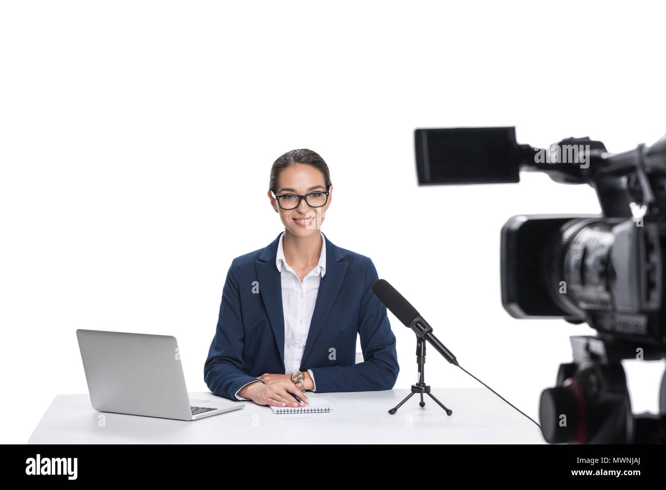 attractive female newscaster sitting at table with laptop, notepad and ...