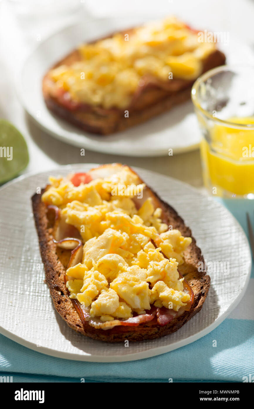 Sourdough bread slices with fried bacon and scrambled eggs Stock Photo