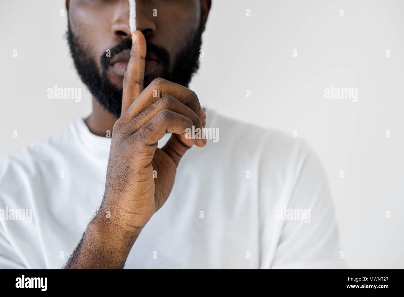 cropped image of african american man with white stripe on face showing silence sign isolated on white Stock Photo