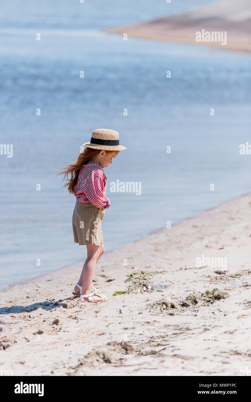 cute little girl in straw hat walking on sand at seashore Stock Photo ...