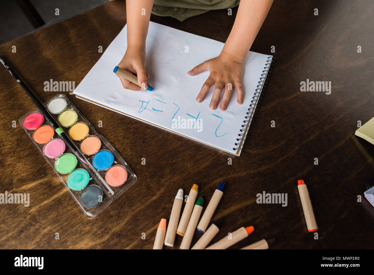 cropped shot of child writing math exercise with crayon in album Stock Photo