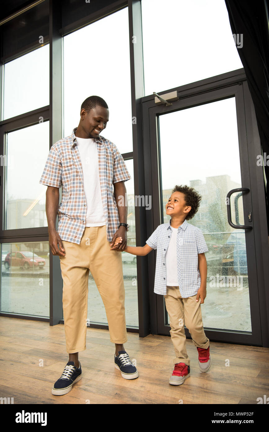 happy african american father and son holding hands and smiling each ...