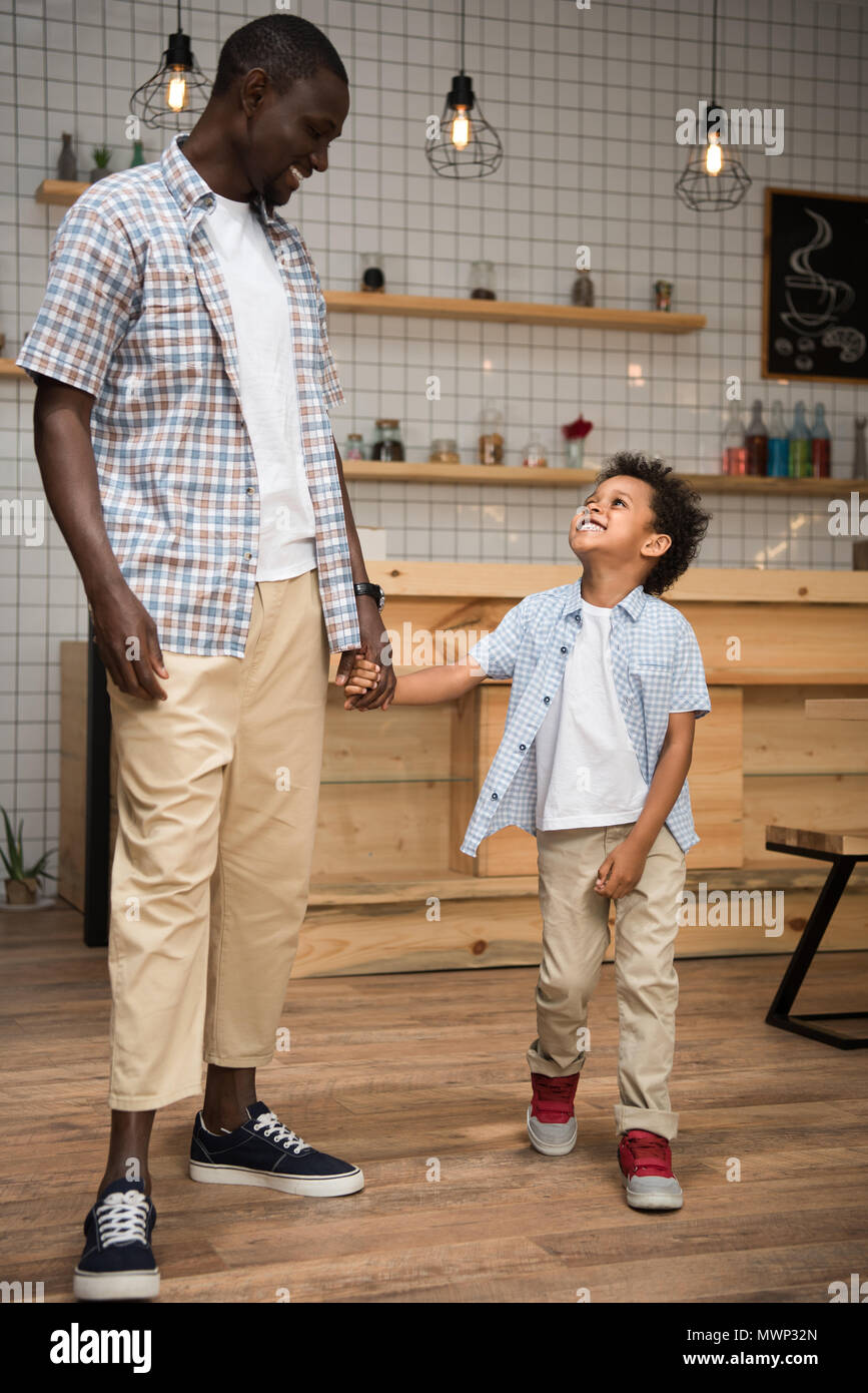 happy african american father and son holding hands and smiling each ...