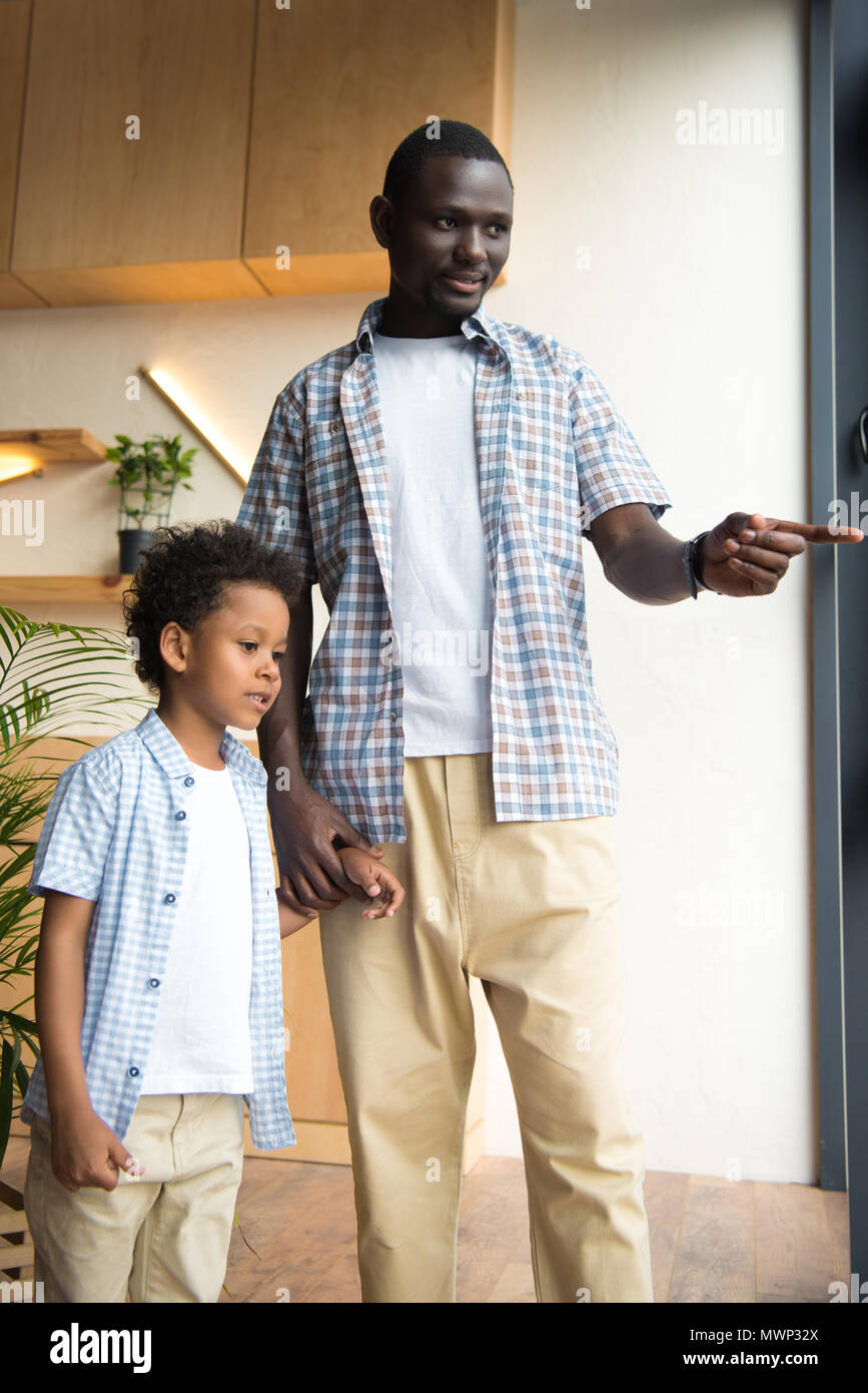 african american father and son standing together and holding hands ...
