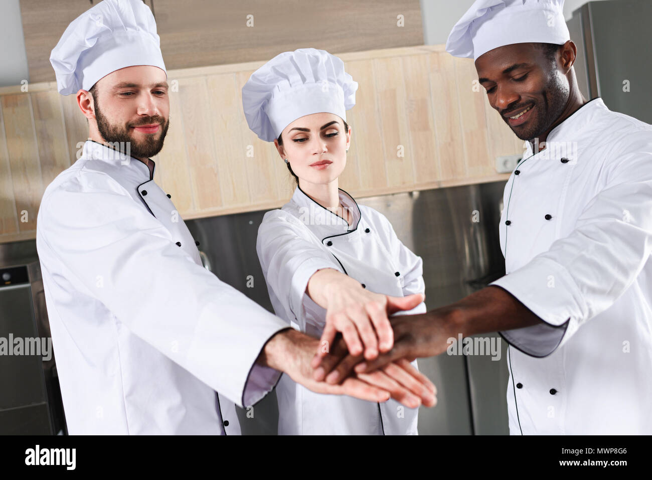 Multiracial chefs team stacking hands together on modern kitchen Stock Photo