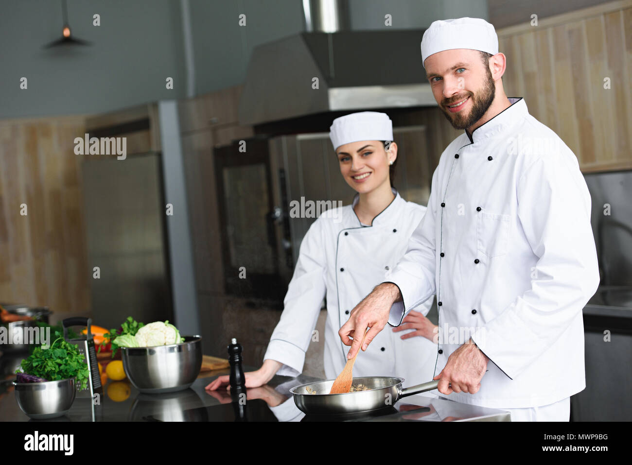 chefs frying vegetables on frying pan at restaurant kitchen Stock Photo