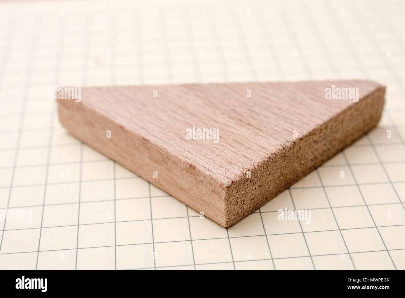 Piece of wood in the shpae of a triangle on paper Stock Photo - Alamy