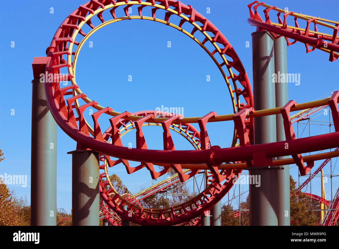 A looping, twisting, red steel rollercoaster thrills passengers with speed and turns. Stock Photo