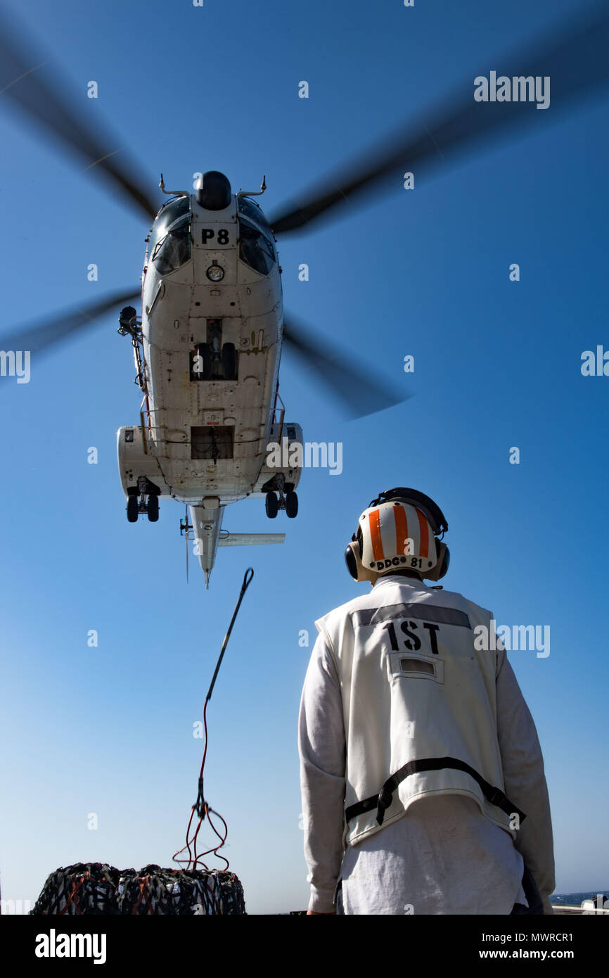 180516-N-AV754-0142 U.S. 5TH FLEET AREA OF OPERATIONS (May 16, 2018) Ensign Nickolas England watches as a Eurocopter AS332 Super Puma helicopter, assigned to the dry cargo and ammunition ship USNS Amelia Earhart (T-AKE 6), delivers cargo to the Arleigh Burke-class guided-missile destroyer USS Winston S. Churchill (DDG 81) during a replenishment-at-sea. Winston S. Churchill is deployed to the U.S. 5th Fleet area of operations in support of maritime security operations to reassure allies and partners and preserve the freedom of navigation and the free flow of commerce in the region. (U.S. Navy p Stock Photo