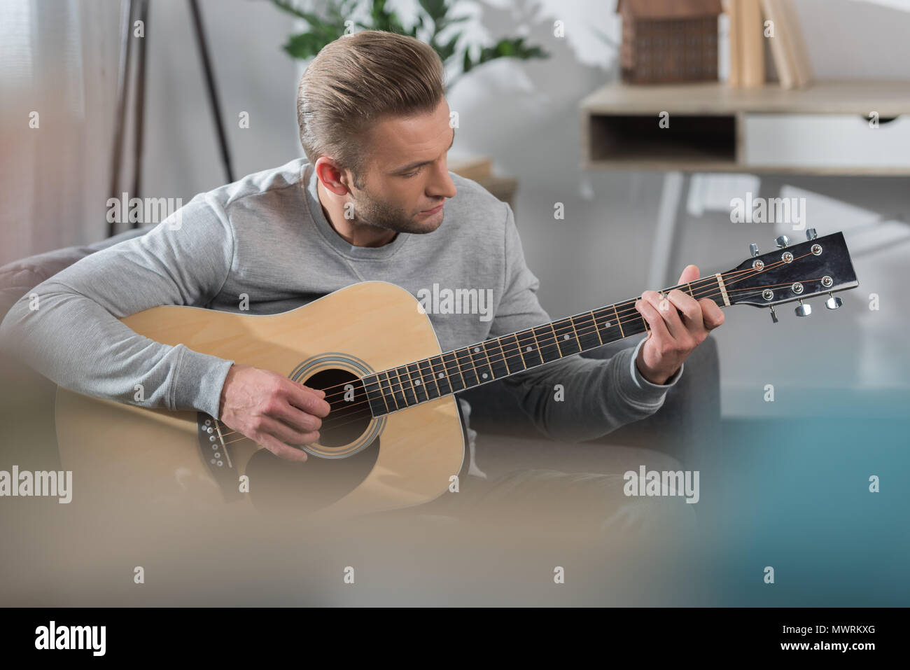 handsome Man sitting on sofa and playing acoustic guitar Stock Photo ...