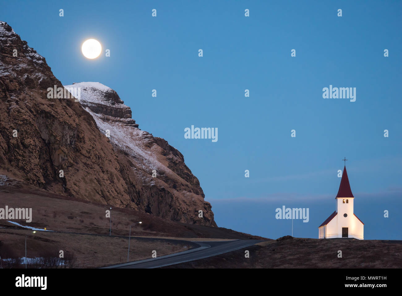 Full moon rising over Vik church in Iceland and a mountain with a