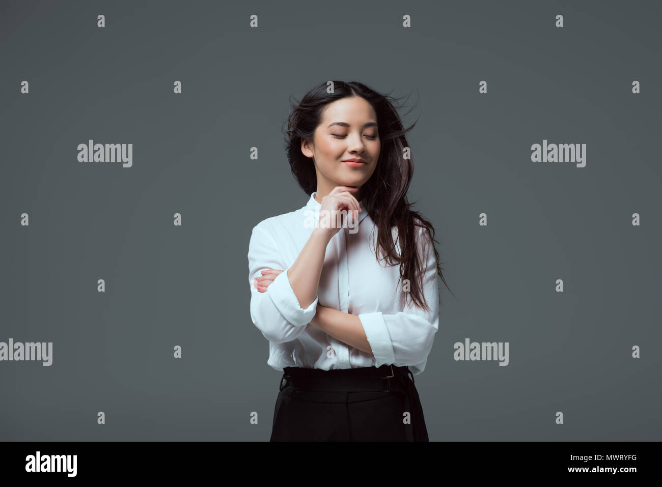 portrait of beautiful smiling asian girl standing with hand on chin ...