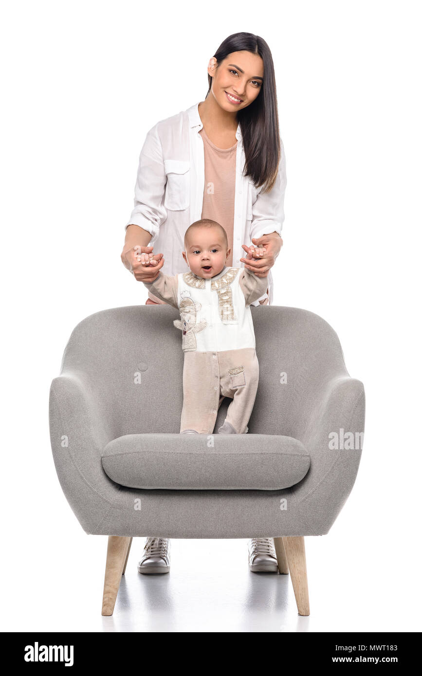 smiling woman with little baby in arm chair isolated on white Stock Photo