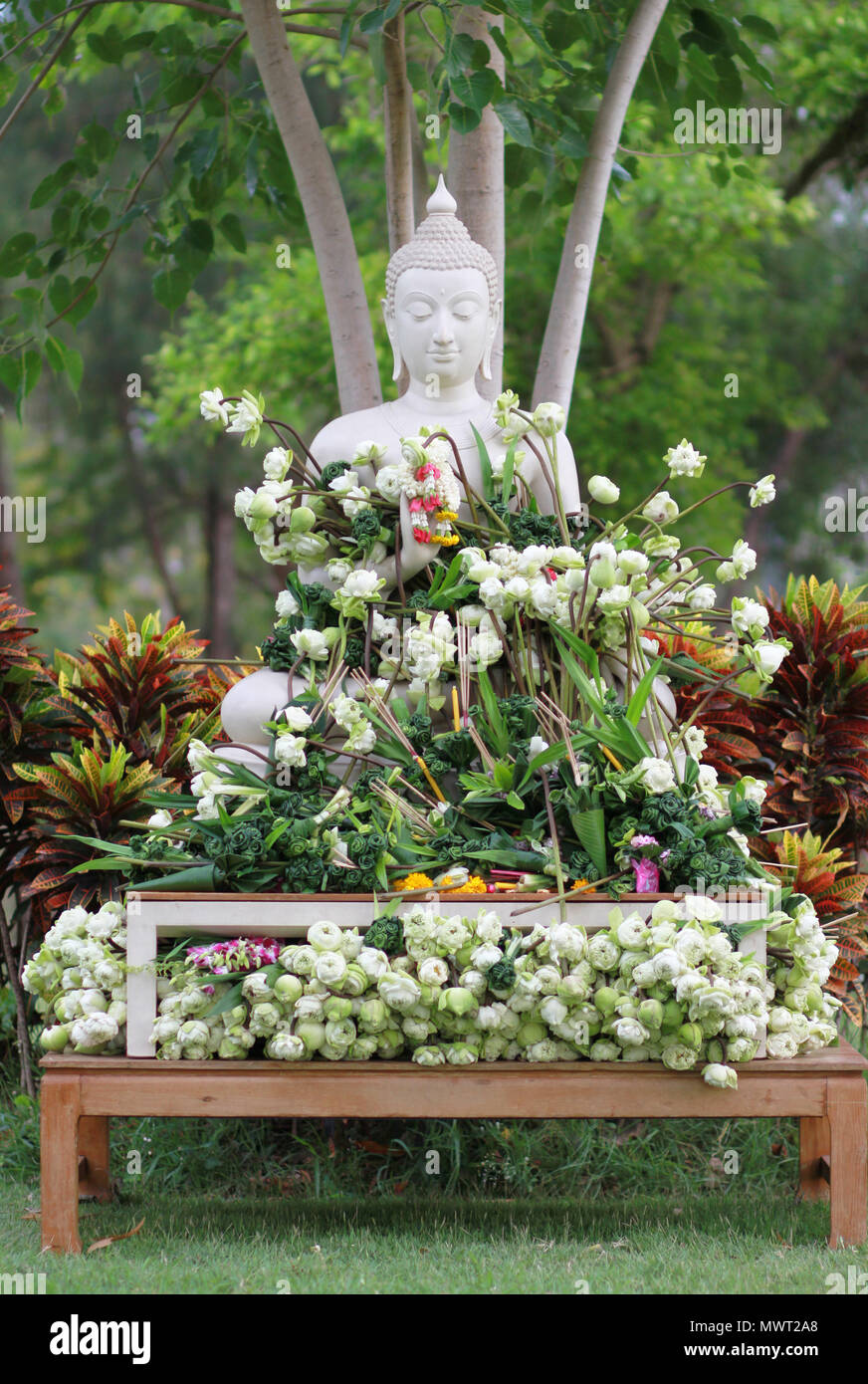 Buddhism worship with offering flowers and garland to buddha statue on
