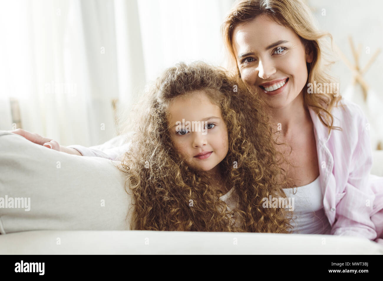happy mother and adorable curly daughter looking at camera Stock Photo ...