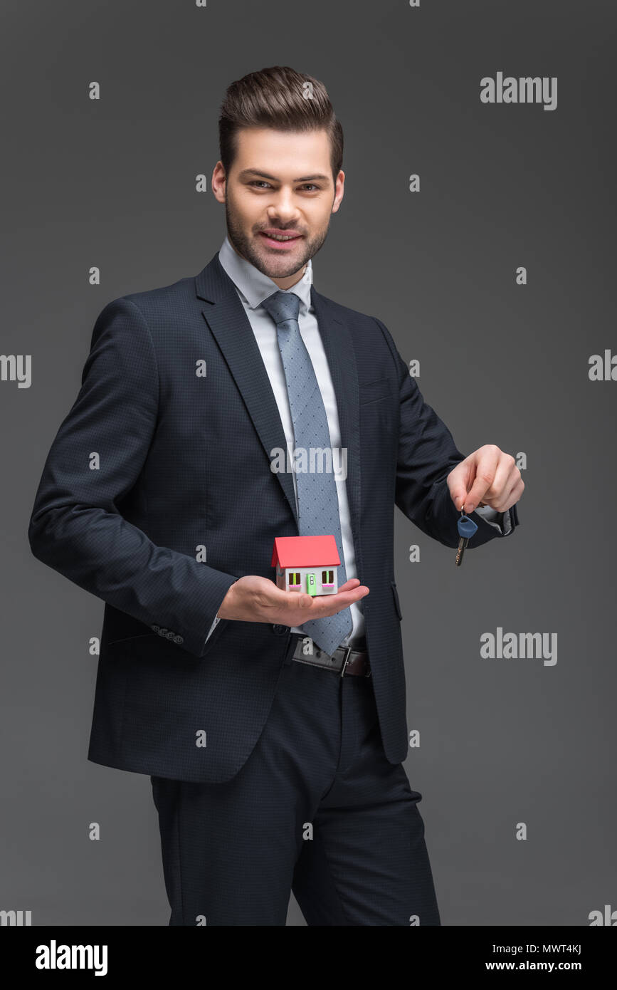 real estate agent holding house model and key, isolated on grey Stock ...