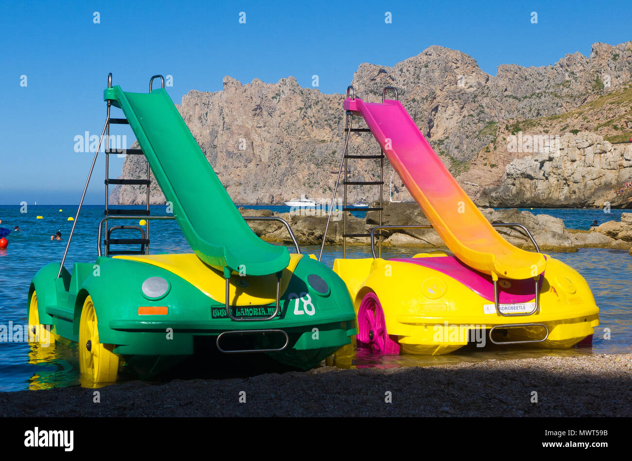 Two brightly coloured pedalos parked on a beach in Cala San Vicente in Mallorca, Spain. Stock Photo