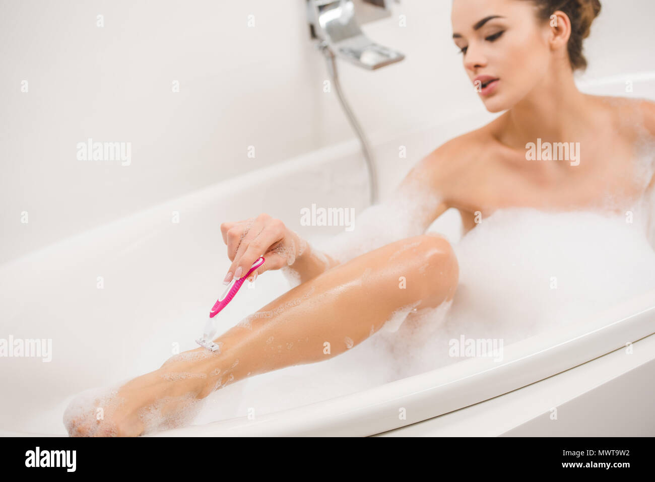 young woman shaving legs while taking bath at home Stock Photo Alamy
