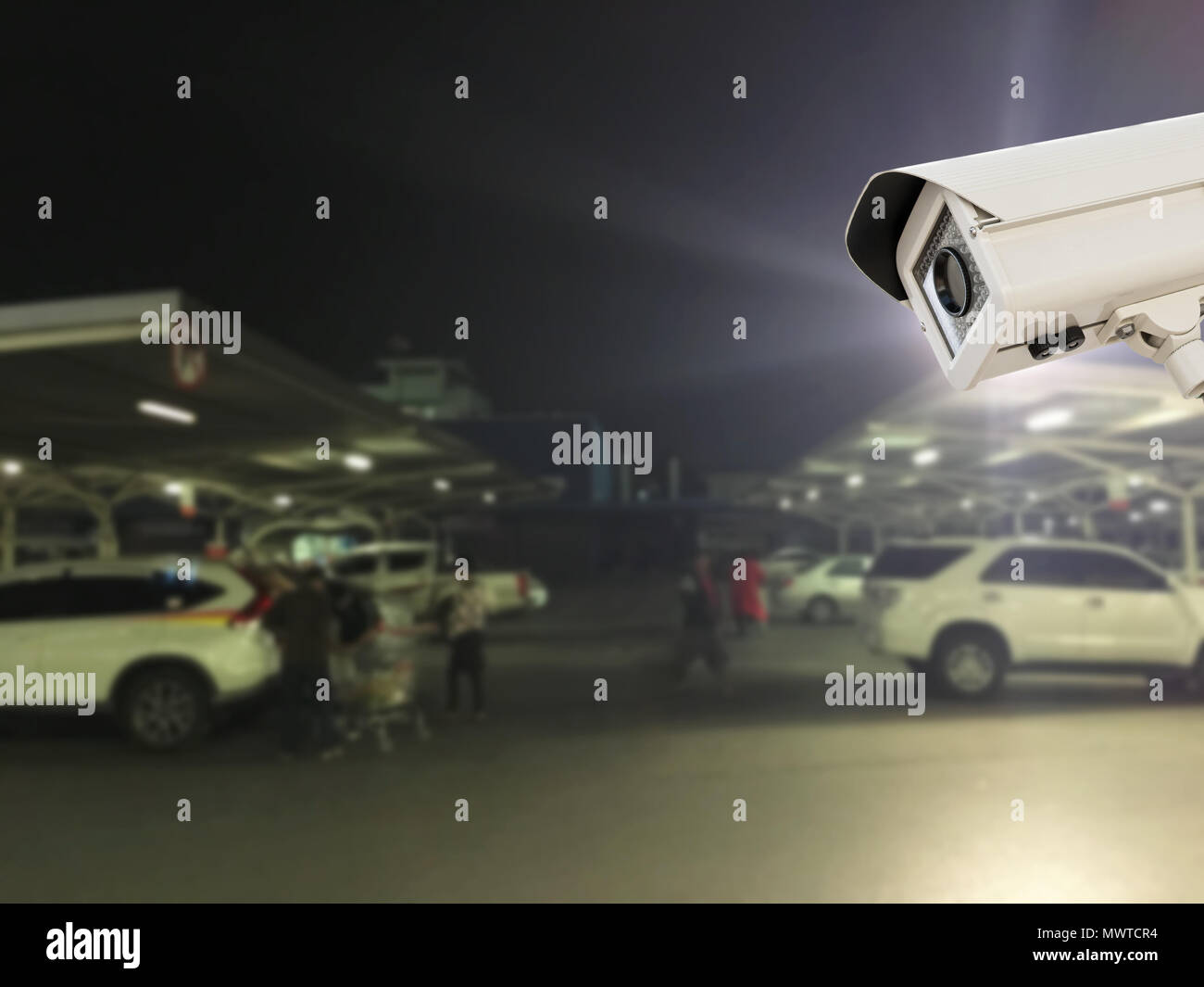 The CCTV Security Camera operating in parking lot car at night time blur  background Stock Photo - Alamy