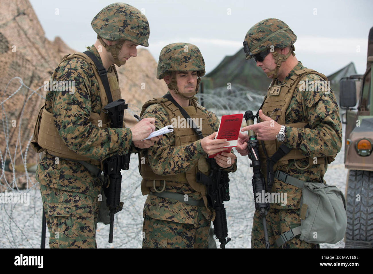 U.S. Marine Corps Capt. Richards Phillips (left) , Maj. Christian Palmer (center), Lieutenant Col. Scott Morrison (right) with Civil Affairs G-9,  III Marine Headquarters Group (III MHG), looking through their field operations guide during Marine Expeditionary Force Exercise 2017 (MEFEX 17) at Range GP 304 on Marine Corps Base Camp Hansen, Okinawa, Japan, April 27, 2017. MEFEX 17, a command and control exercise conducted in a simulated deployed environment, is designed to synchronize and bring to bear the full spectrum of III MEF, while remaining ready to provide the Marine Corps with an exper Stock Photo