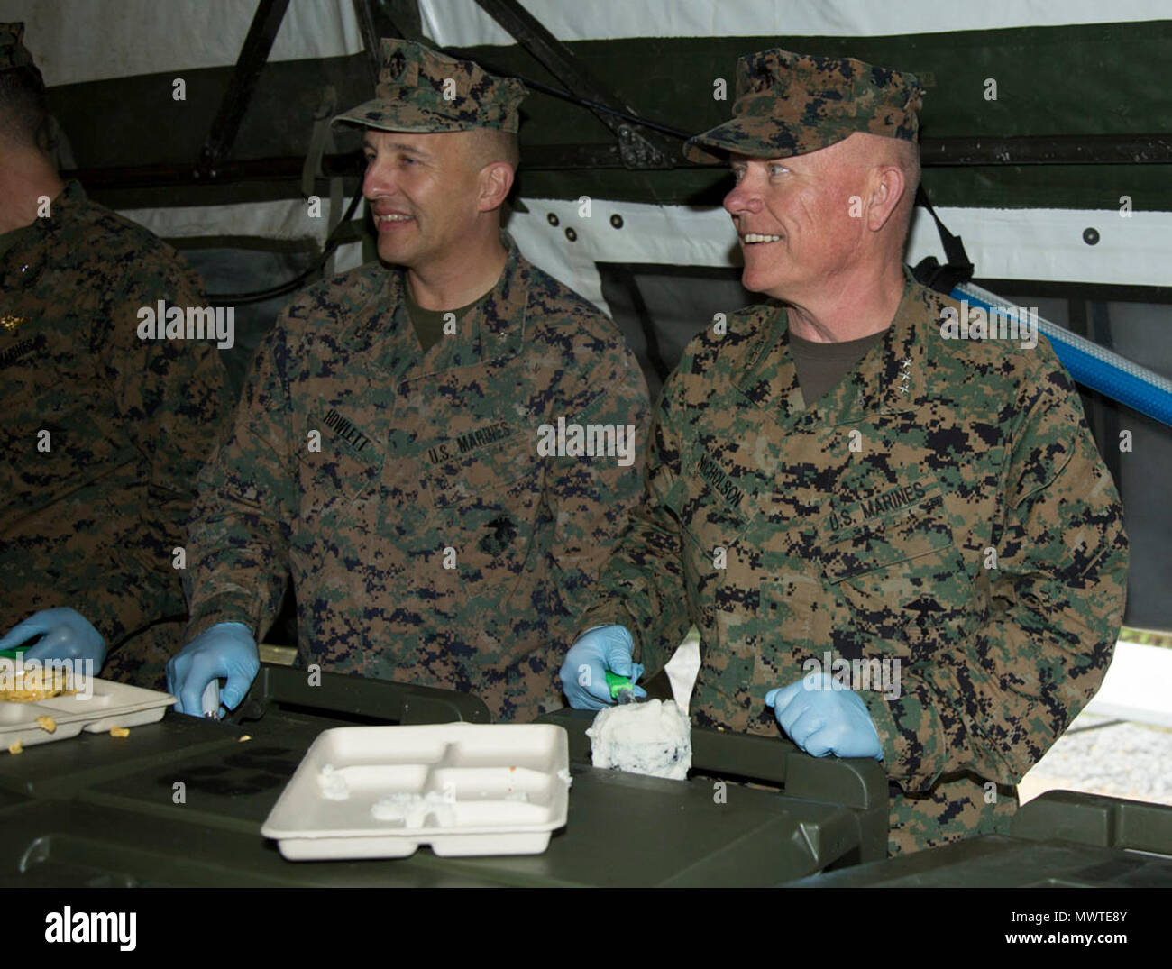U.S. Marine Corps (left) Col. Brian M. Howlett, the Camp Commander at Camp Hansen, (right) Lt. Gen. Lawrence Nicholson, the Okinawa Area and III Marine Expeditionary Force Commanding General with III Marine Headquarters Group (III MHG), serves chow to service members during Marine Expeditionary Force Exercise 2017(MEFEX 17) at Range GP 304 on Marine Corps Base Camp Hansen, Okinawa, Japan, April 27, 2017. MEFEX 17, a command and control exercise conducted in a simulated deployed environment, is designed to synchronize and bring to bear the full spectrum of III MEF, while remaining ready to prov Stock Photo