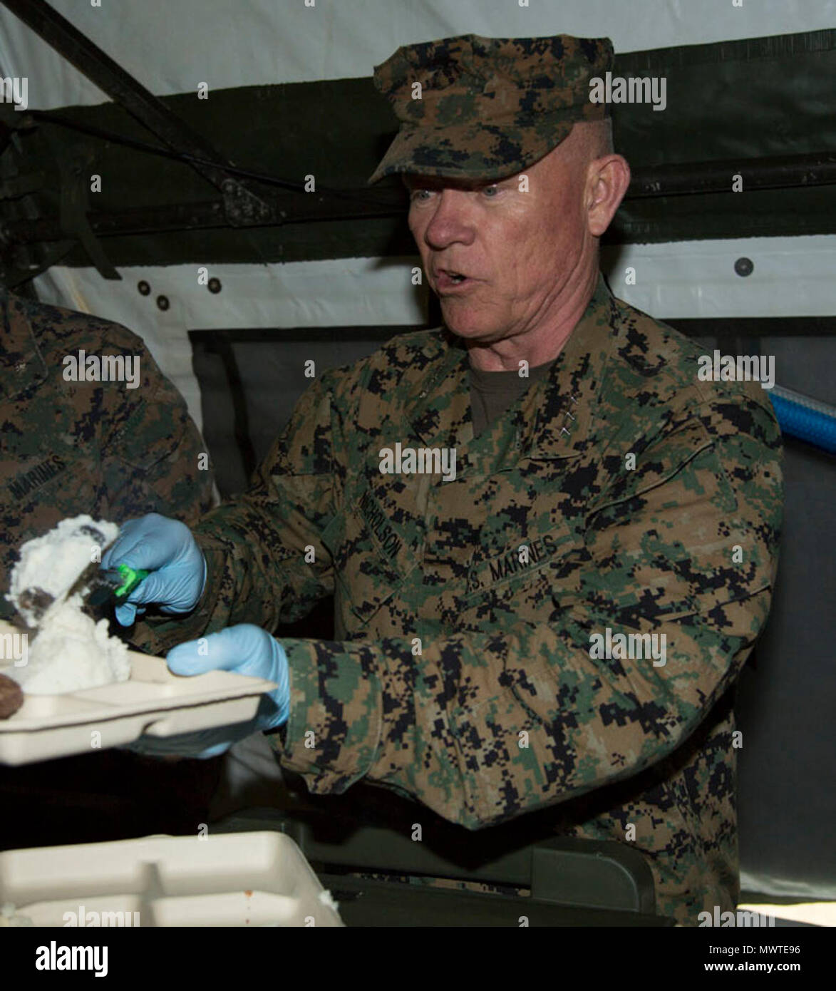 U.S. Marine Corps Lt. Gen. Lawrence Nicholson, the Okinawa Area and III Marine Expeditionary Force Commanding General  with III Marine Headquarters Group (III MHG), serves chow to service members during Marine Expeditionary Force Exercise 2017(MEFEX 17) at Range GP 304 on Marine Corps Base Camp Hansen, Okinawa, Japan, April 27, 2017. MEFEX 17, a command and control exercise conducted in a simulated deployed environment, is designed to synchronize and bring to bear the full spectrum of III MEF, while remaining ready to provide the Marine Corps with an experienced staff capable of integrating wi Stock Photo