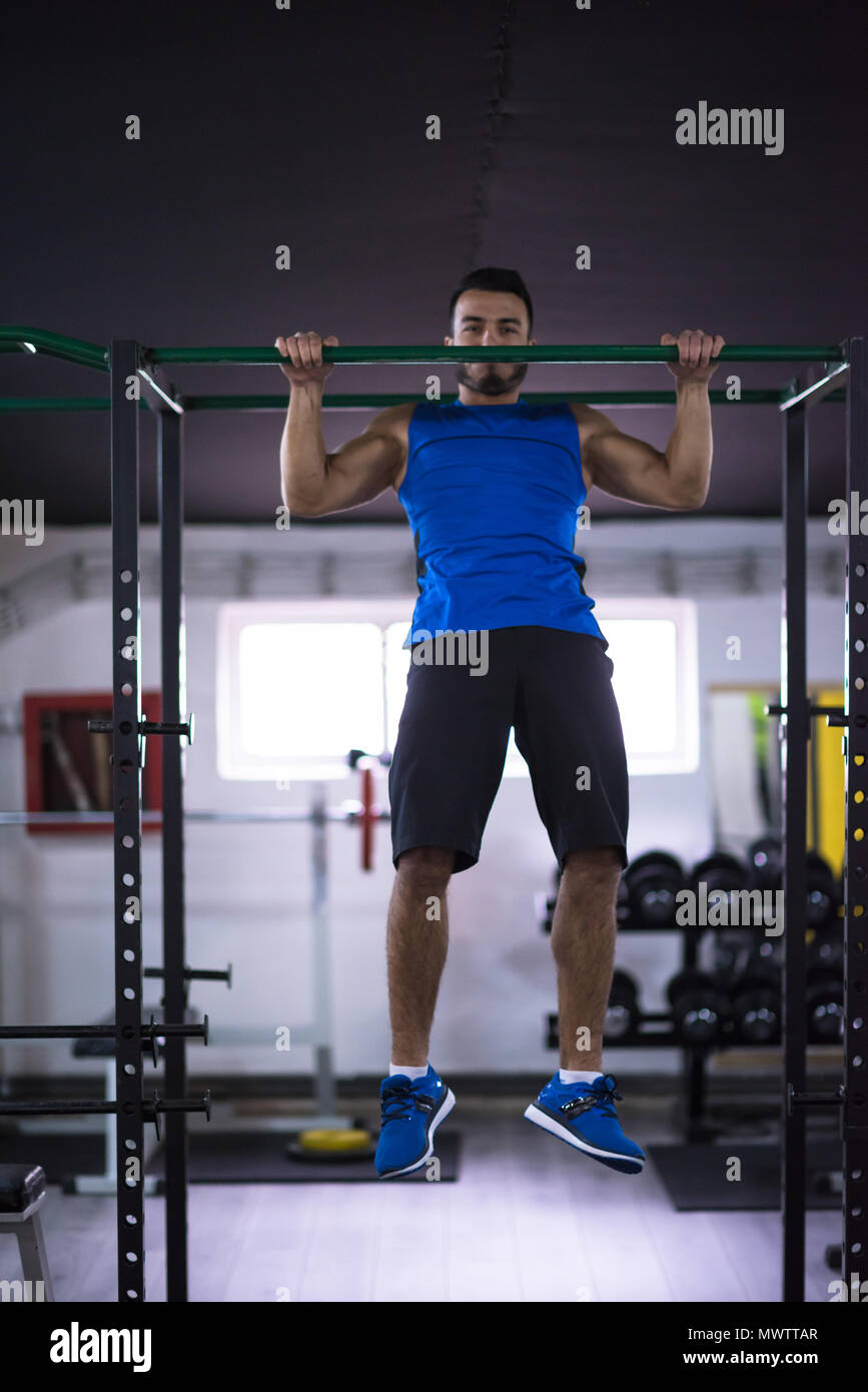 young muscular man doing pull ups on the horizontal bar as part of ...
