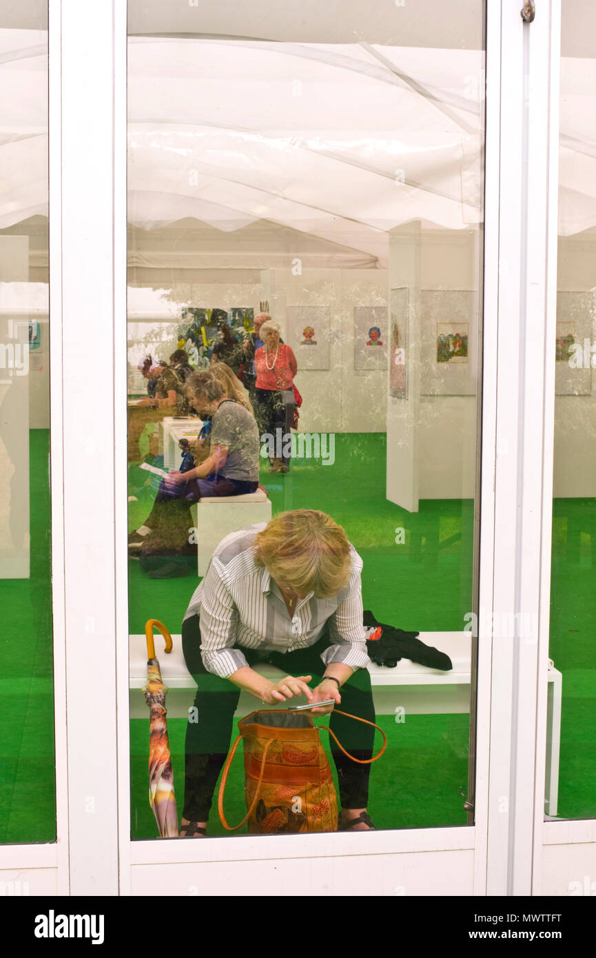 Woman texting on her smartphone in the art gallery at Hay Festival 2018 Hay-on-Wye Powys Wales UK Stock Photo