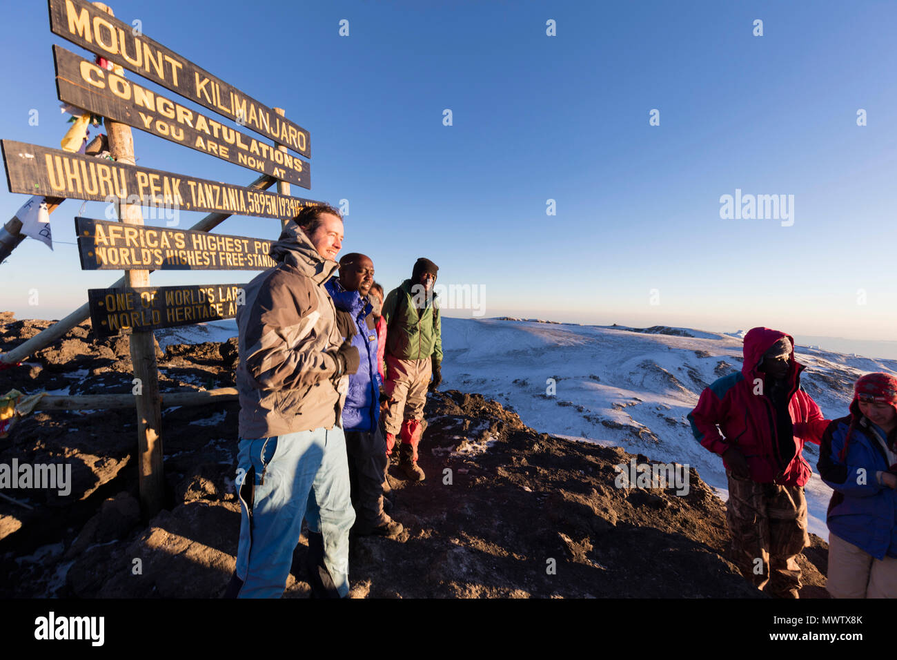 Climbers at summit sign and views on Mount Kilimanjaro, Kilimanjaro National Park, UNESCO World Heritage Site, Tanzania, East Africa, Africa Stock Photo