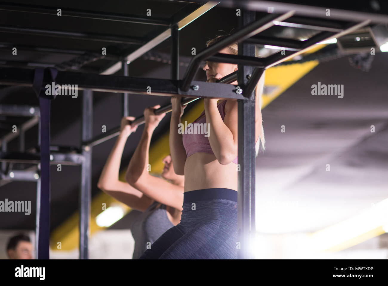 group of young muscular athletes doing pull ups on the horizontal bar ...