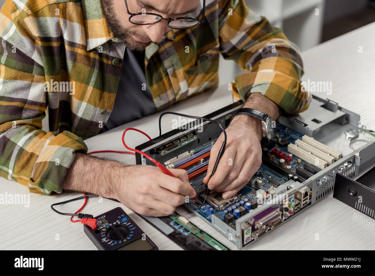 cropped image repairman using multimeter while fixing computer motherboard Stock Photo