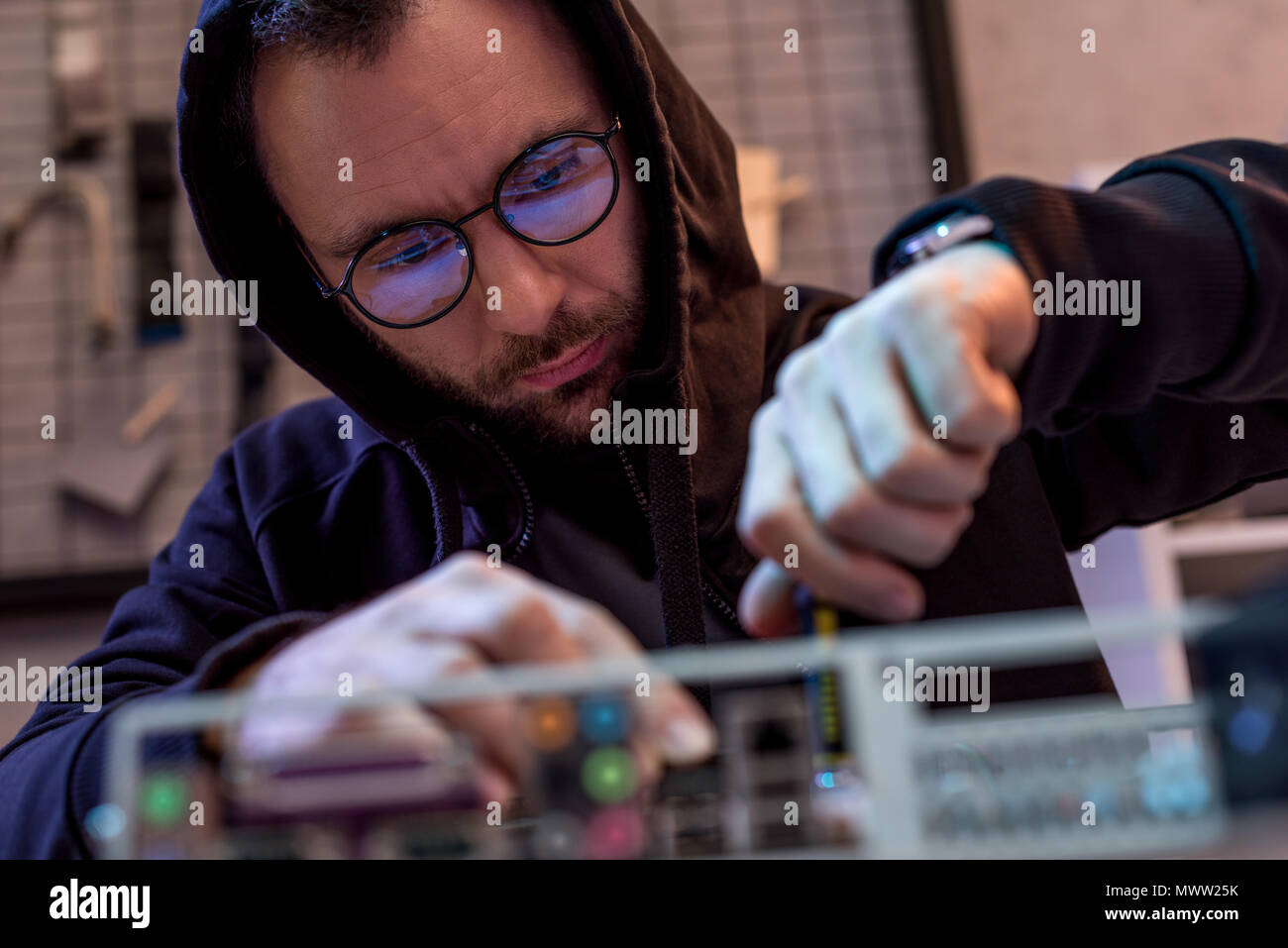 man in hoodie fixing broken pc Stock Photo