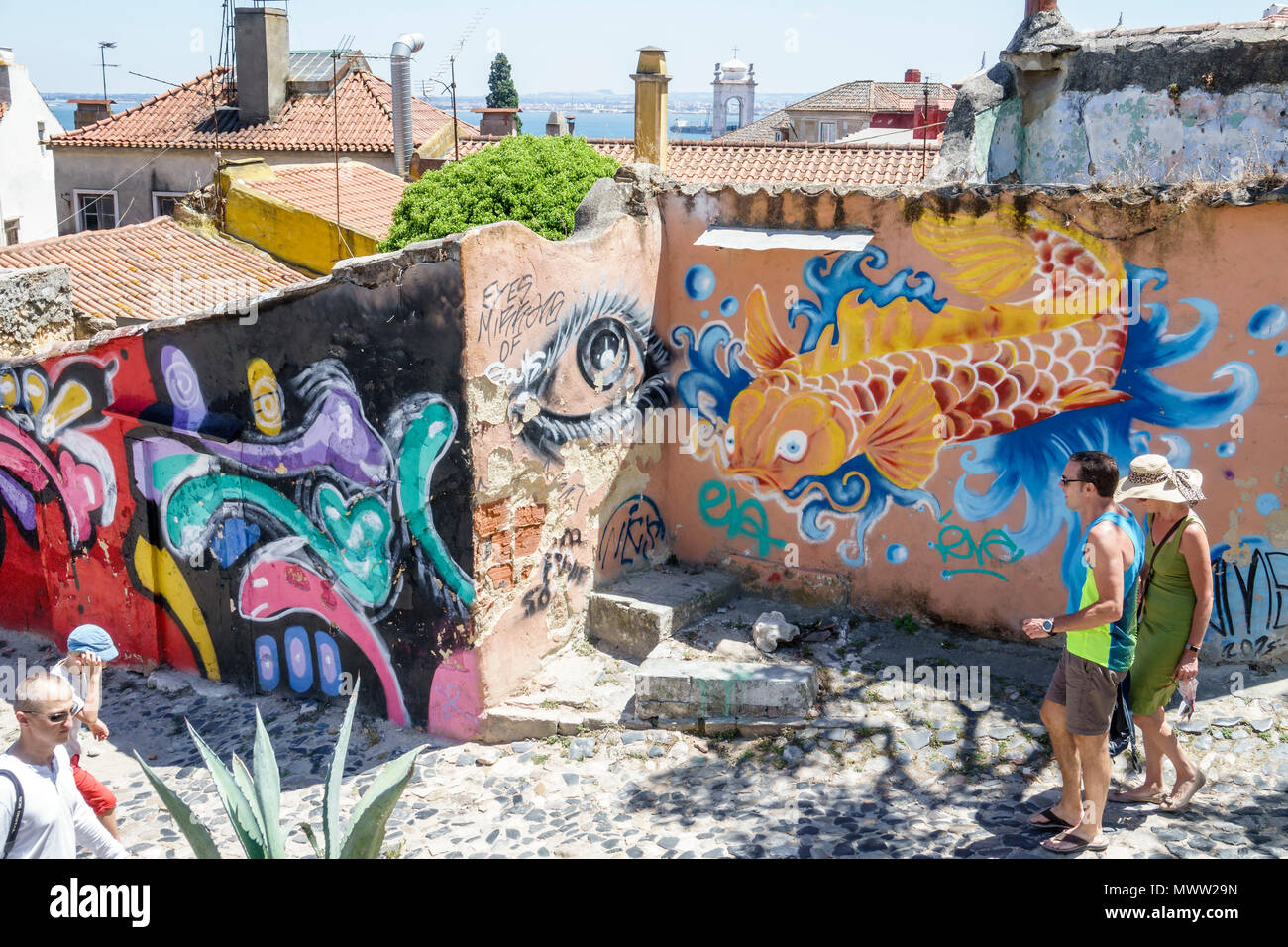 Lisbon Portugal,Alfama,historic neighborhood,graffiti,ruins,street art,man men male,woman female women,couple,walking,Hispanic,immigrant immigrants,Po Stock Photo