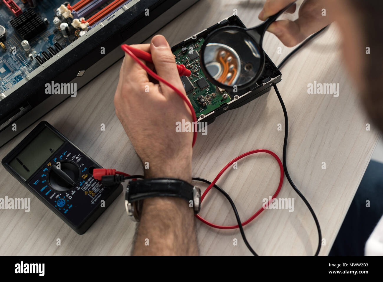 cropped image of repairman using multimeter while testing hard disk drive Stock Photo
