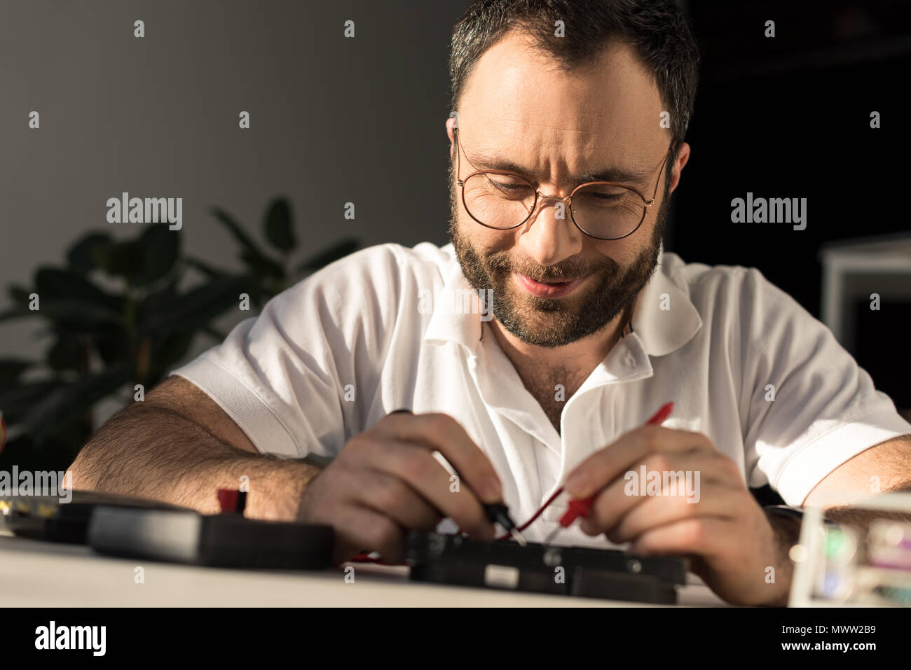 smiling man using multimeter while fixing pc Stock Photo