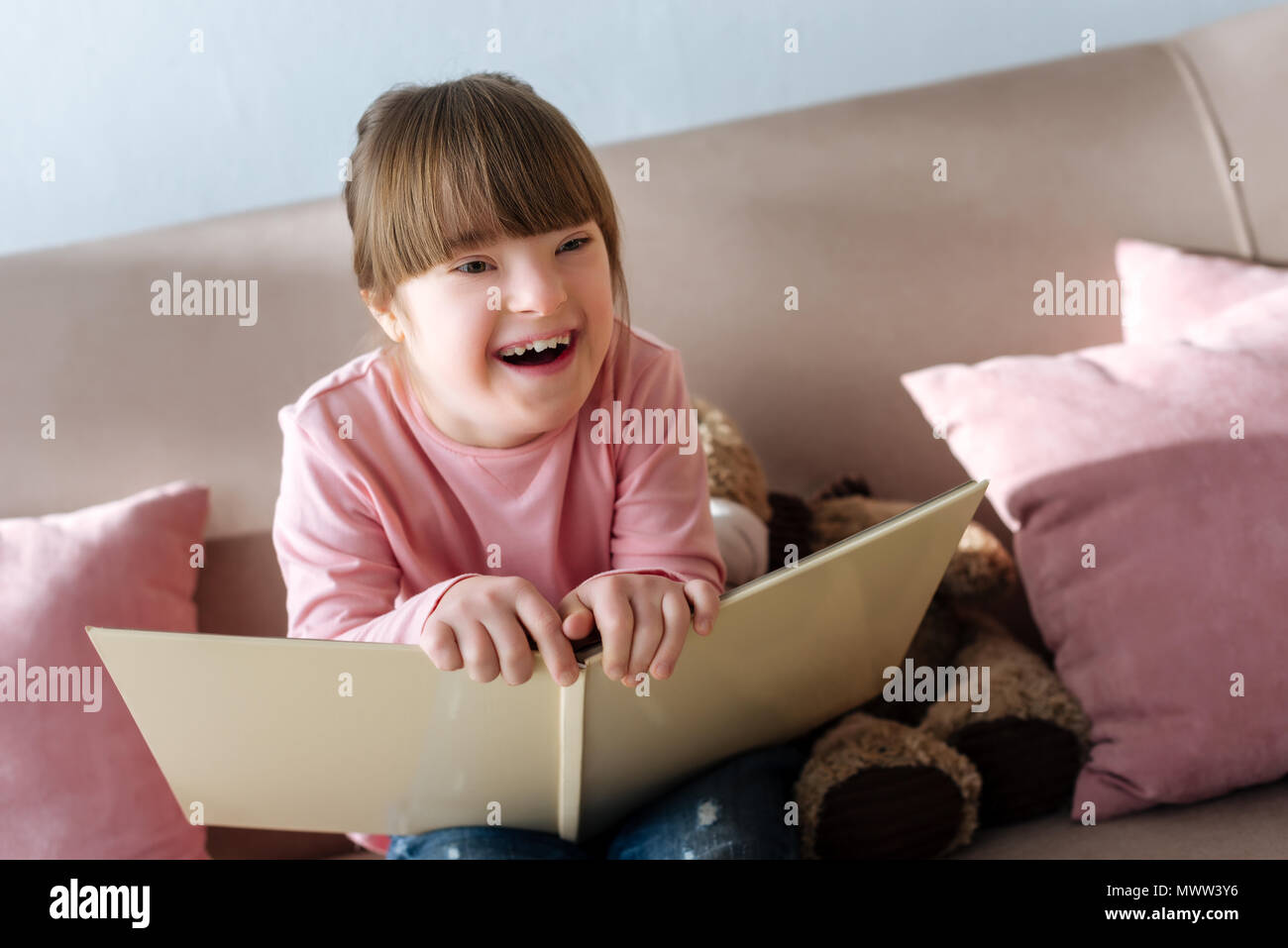 Kid with down syndrome holding book and laughing Stock Photo