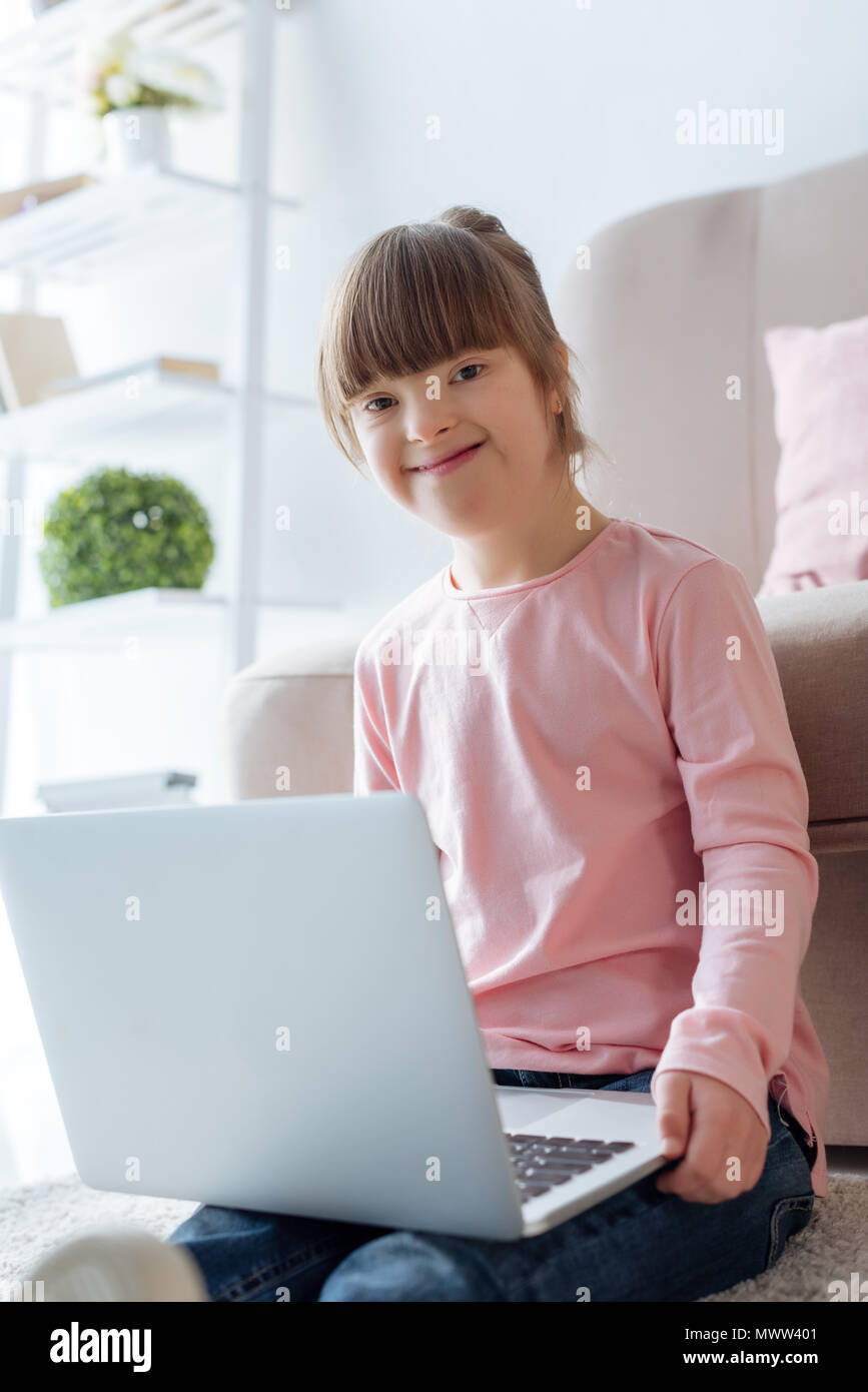 Smiling kid with down syndrome using laptop Stock Photo