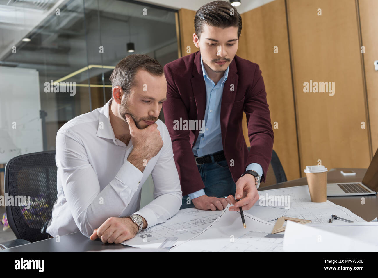 thoughtful architects brainstorming over building plans at office Stock Photo