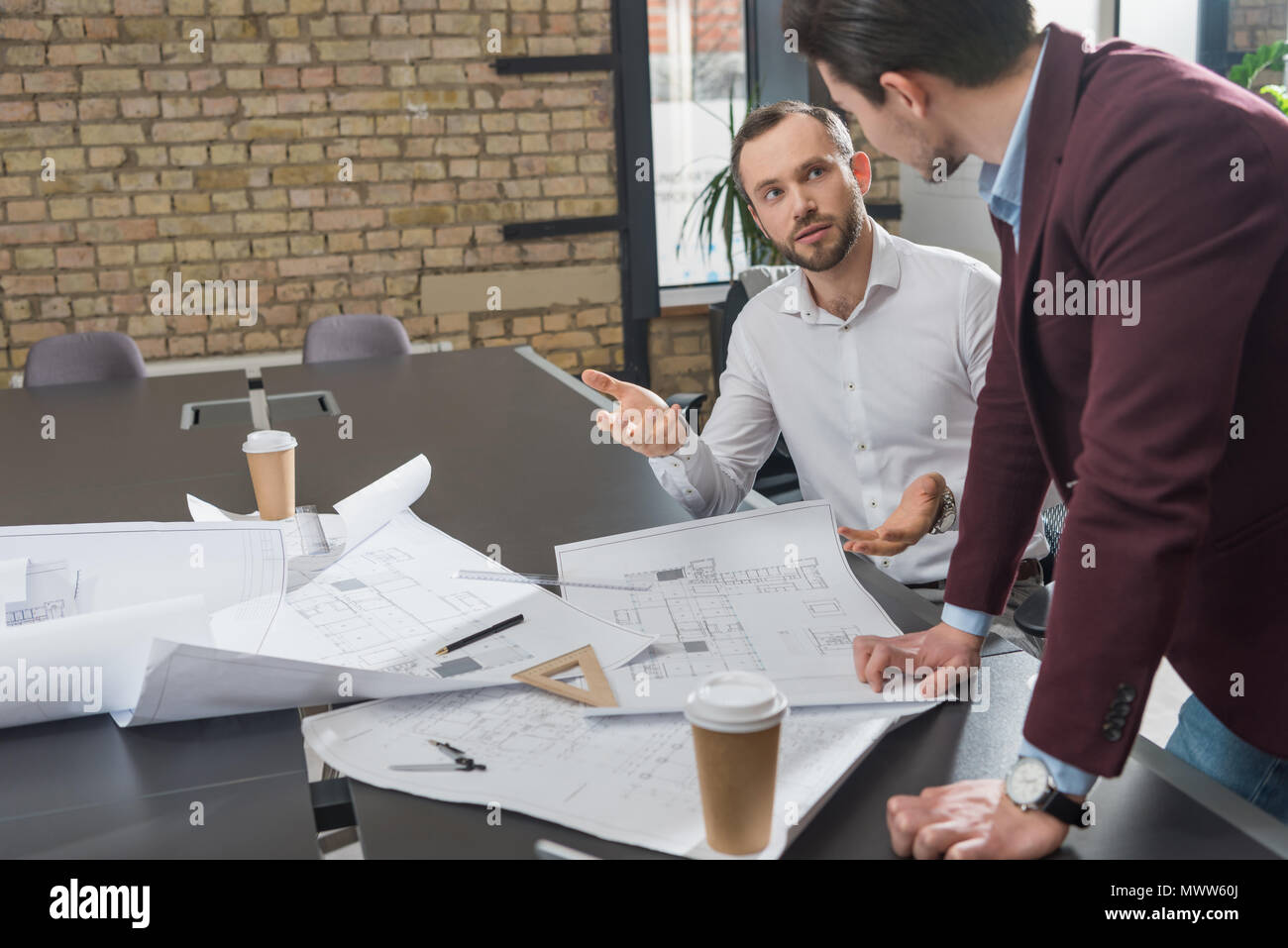 successful architects brainstorming over building plans at office Stock Photo