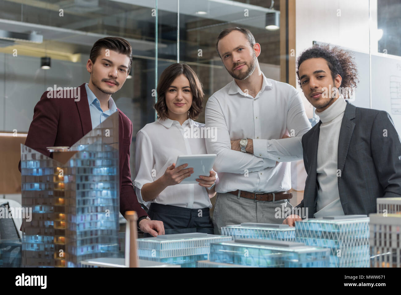 group of successful architects standing next to building models at