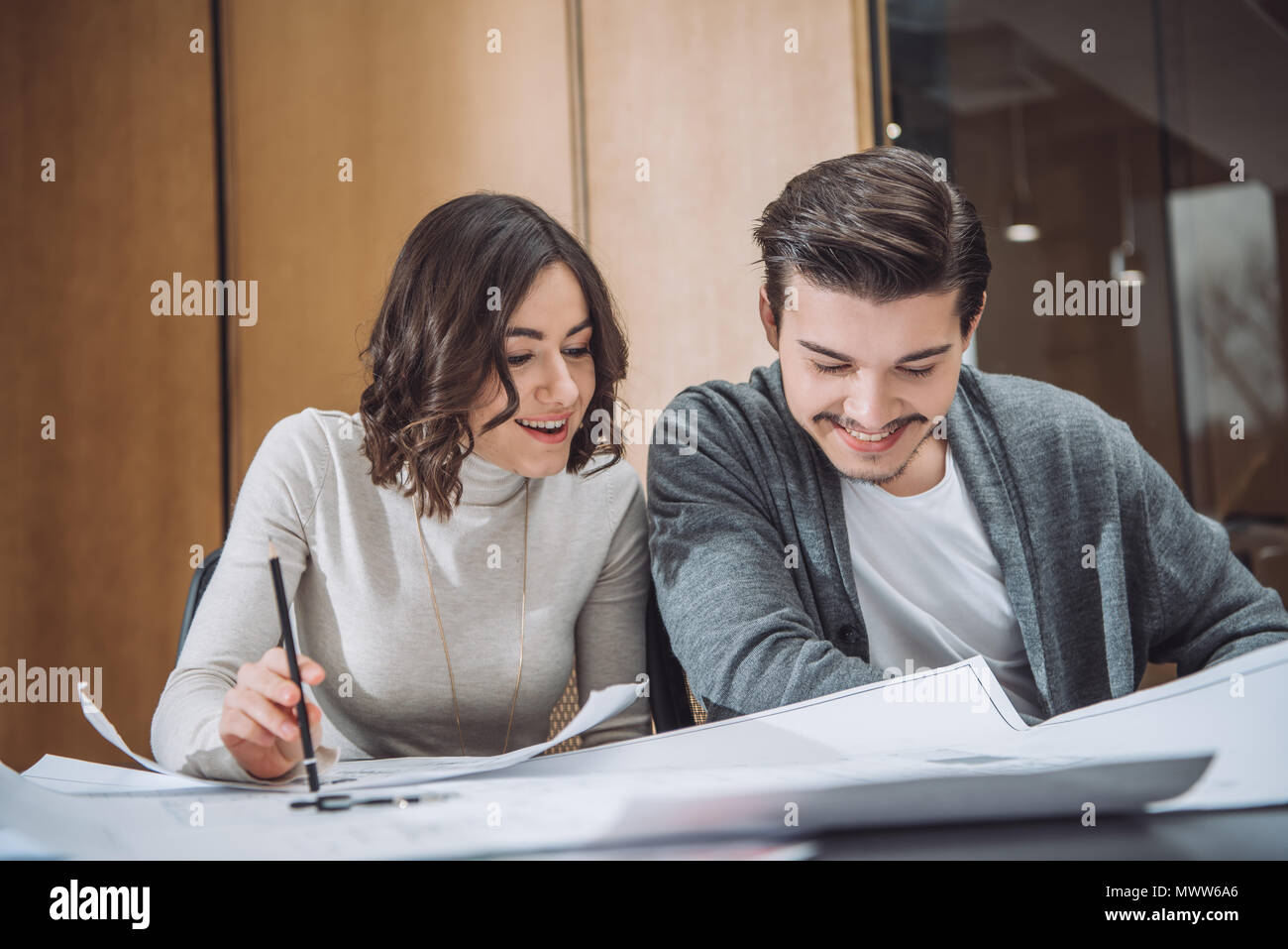 happy young architects working with building plans together at office ...