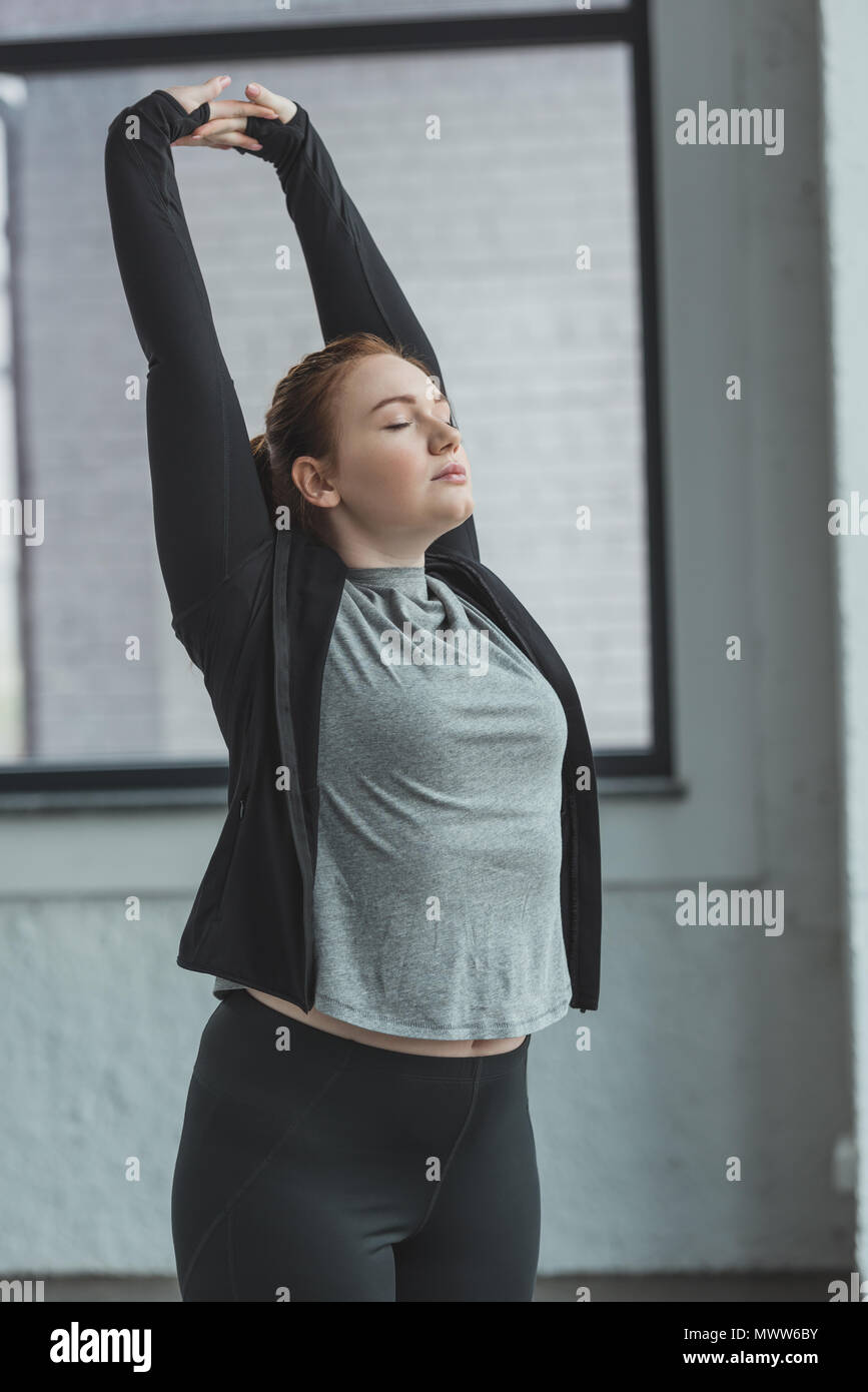 Curvy girl stretching arms in gym Stock Photo - Alamy