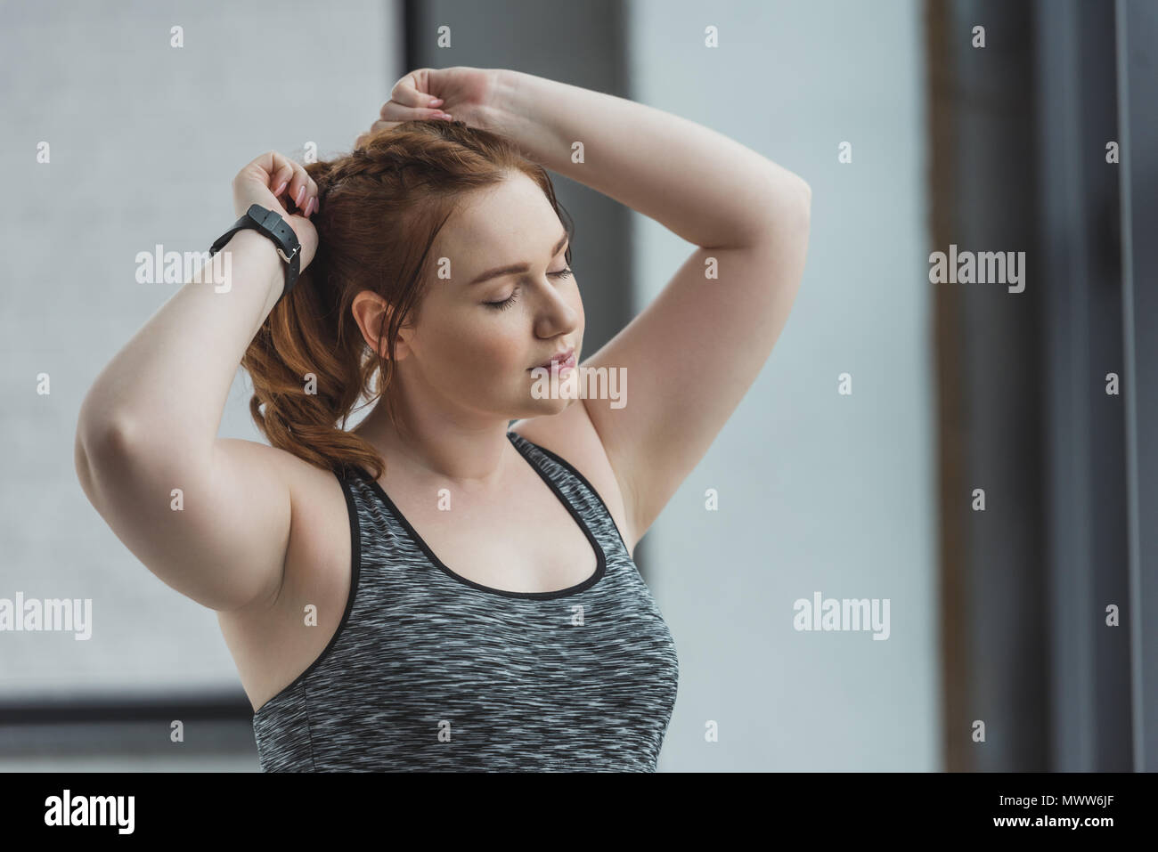 Obese girl fixing her hair in gym Stock Photo