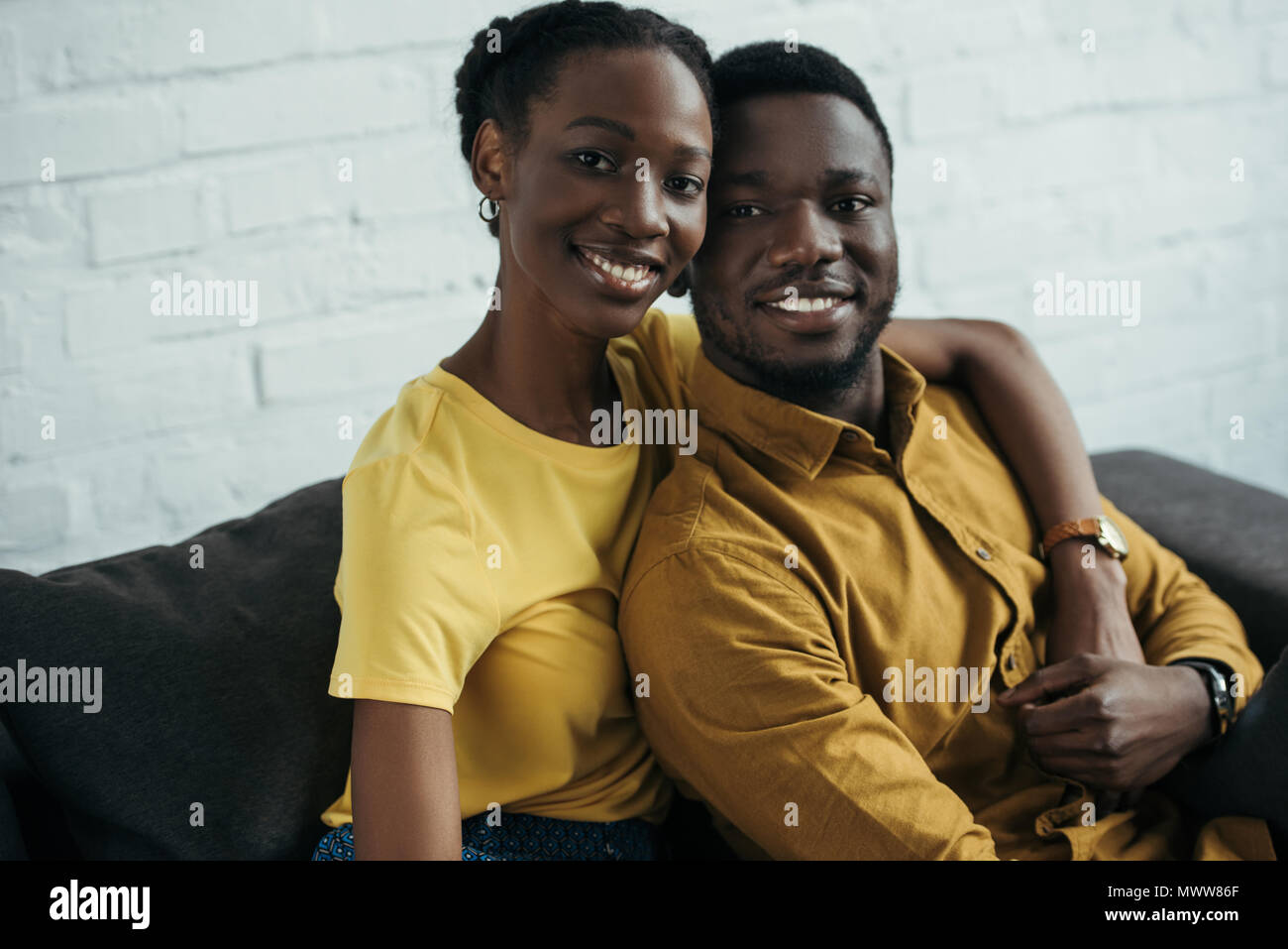 happy young african american couple in yellow shirts hugging and ...